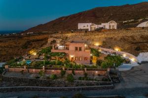 a house sitting on top of a hill at night at AURORA VILLA by K&K in Oia