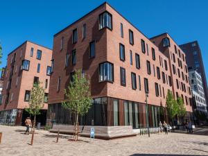 - un grand bâtiment en briques avec des personnes qui marchent devant dans l'établissement Hotel Odeon, à Odense