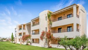 an apartment building with trees in front of it at Golden Bay Hotel Apartments in Malia