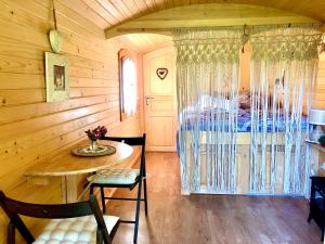 een slaapkamer met een bed en een tafel en stoelen bij Roulotte La Chouette des Granges in Les Salles-Lavauguyon