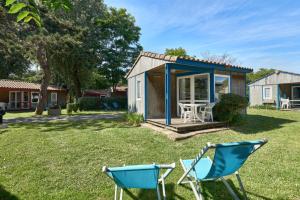 a tiny house with two chairs in the yard at Camping La Brande in Le Château-dʼOléron