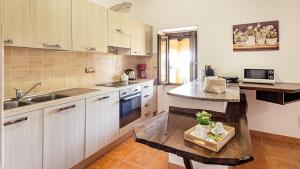uma cozinha com armários brancos, um lavatório e uma mesa em Welcomely - Guesthouse Kadossene Alghero em Alghero