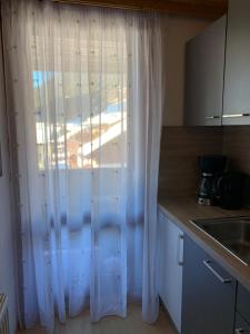 - une cuisine avec une fenêtre dotée de rideaux blancs dans l'établissement Ski und Therme 1, à Bad Kleinkirchheim