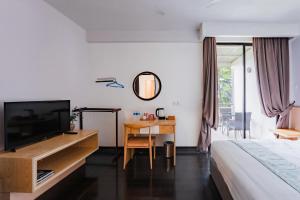 une chambre avec un lit et un bureau avec une télévision dans l'établissement Mountain Valley Resort, à Kampong Kundassan