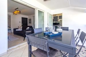a dining room and living room with a glass table at Safari - Apt rénové proche des Roches Noires - Saint Gilles les Bains in Saint-Gilles les Bains