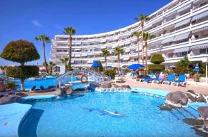 a large swimming pool with a hotel in the background at Club Atlantis studio 160 - Playa de Las Americas in Adeje