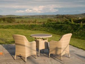 a table and chairs on a patio with a view at Tyddyn Haidd in Amlwch