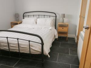 a bedroom with a bed with white sheets and a tiled floor at Tyddyn Haidd in Amlwch