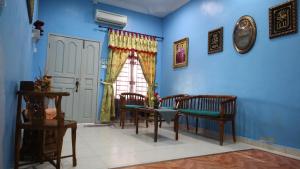 uma sala de jantar com paredes azuis e uma mesa e cadeiras em D' Pelangi Homestay Kluang em Keluang