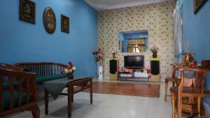 uma sala de estar com paredes azuis e uma televisão em D' Pelangi Homestay Kluang em Keluang