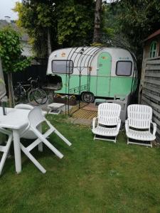 a picnic table and two chairs and a trailer at Gite Atypique Caravane Vintage et piscine ouverte du 15 Mai au 30 Septembre in Godinne