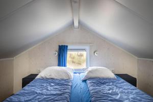 two beds in a room with a window at Strandbungalows Vrouwenpolder in Vrouwenpolder