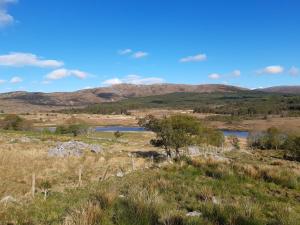 a field with a lake and mountains in the background at Back2Roots - Beautifully Restored Cottage, Doochary in Doochary