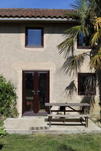 a wooden bench in front of a building with a door at L'Atelier @ Le Prielle in Madiran