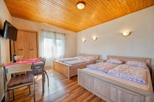 two beds in a room with a table and a desk at Kwatery u Zdzicha in Gowidlino