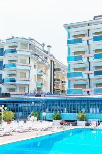 un hôtel avec une piscine en face d'un bâtiment dans l'établissement Hotel Monaco & Quisisana, à Lido di Jesolo