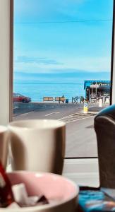 a view of the ocean from a window with a cup at gwesTY Guest House in Aberystwyth
