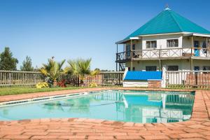 a swimming pool in front of a house at Tsitsikamma Cottages in Witelsbos
