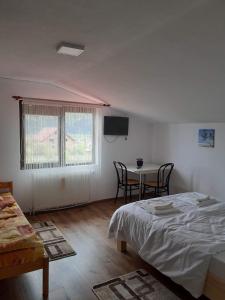 a bedroom with a bed and a table with chairs at Casa Popa in Gura Humorului