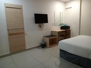 een slaapkamer met een bed, een bureau en een televisie bij AVENUE BANGI HOTEL in Kajang