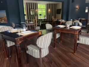 une salle à manger avec des tables en bois et des chaises blanches dans l'établissement Hotel Randduin, à Oostkapelle