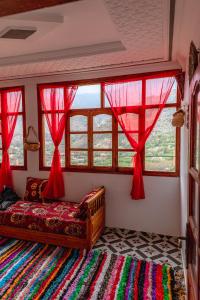 um quarto com cortinas vermelhas, um sofá e janelas em Amazigh Family Riad em Imlil