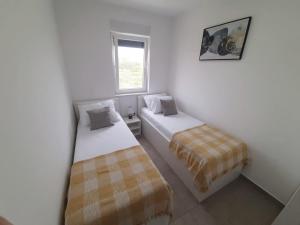 two beds in a small room with a window at Apartments Anda Nin in Nin