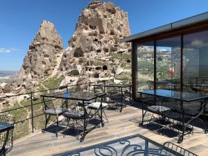 a restaurant with tables and chairs on a balcony with mountains at Caldera Cave Hotel & Restaurant in Uçhisar