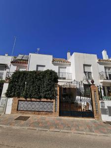 a white house with a black gate and ivy at Casa adosada - Los Boliches - Fuengirola in Fuengirola