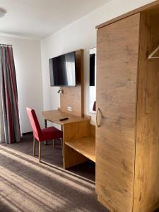 ein Hotelzimmer mit einem Schreibtisch und einem roten Stuhl in der Unterkunft Gasthaus zum Ochsen in Westernhausen