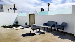 um pátio com cadeiras e uma mesa numa parede branca em Arrecife exclusive beach house em Arrecife