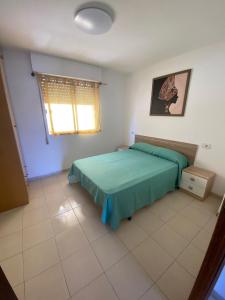 ein Schlafzimmer mit einem grünen Bett und einem Fenster in der Unterkunft ED. MISTRAL VIDABER in Oropesa del Mar