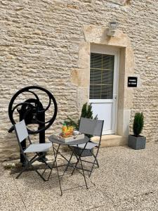 a table and two chairs next to a building at Chambre du verger in Francheville