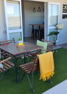 a table and chairs with a yellow towel on them at Bellas Cottage in Langebaan