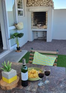 a table with two glasses of wine and a plate of food at Bellas Cottage in Langebaan