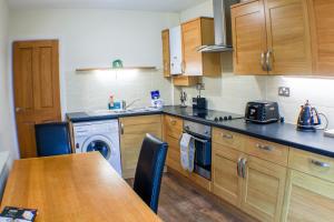 a kitchen with wooden cabinets and a table and a dishwasher at 18 Sea View Close in Scarborough