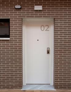 una porta bianca su un edificio di mattoni con il numero di Apartamentos La Espadaña a Rota
