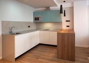 a kitchen with white cabinets and a sink at Apartamentos La Espadaña in Rota