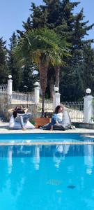 two people laying on towels next to a swimming pool at Perivolos Apartments in Dhërmi