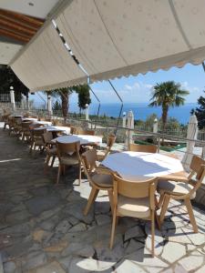 a row of tables and chairs with the ocean in the background at Perivolos Apartments in Dhërmi