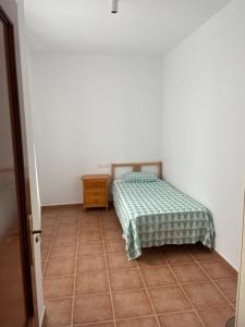 een kleine slaapkamer met een bed en een tegelvloer bij Alojamiento EL BUTAKA in Cala