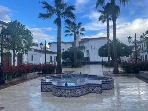 a fountain in the middle of a courtyard with palm trees at Alojamiento EL BUTAKA in Cala