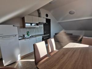 cocina con mesa, sillas y nevera en Apartment Porat 2 en Ugljan