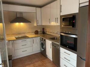 a kitchen with white cabinets and a washer and dryer at Alojamiento EL BUTAKA in Cala