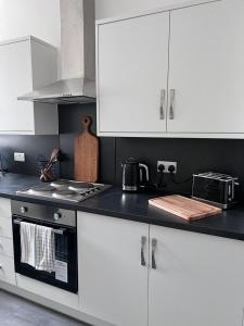 cocina con armarios blancos y encimera negra en Inxpress Luxury Apartment Driffield en Great Driffield