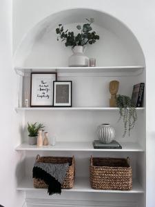 a white shelf with two baskets and pictures on it at Inxpress Luxury Apartment Driffield in Great Driffield