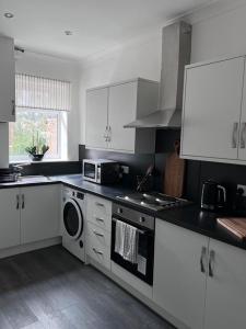 a kitchen with white cabinets and a stove top oven at Inxpress Luxury Apartment Driffield in Great Driffield