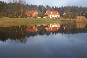a house is reflected in the water of a lake at Siedlisko Pod Dębem in Wilimy