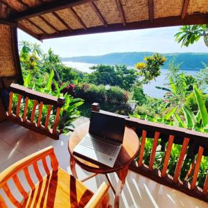 een laptop op een tafel op een balkon bij Sakti OceanView Nusa Penida in Nusa Penida