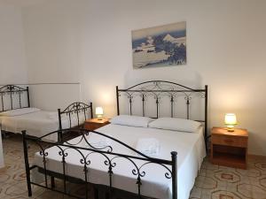 two beds in a room with two lamps on tables at Casa Il Pesco in Noto